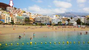 ロス・クリスティアーノスにあるOcean View Cactus I , over Los Cristianos, Playa las Vistasの水中の人々と建物のある浜