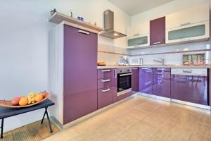 a kitchen with purple cabinets and a bowl of fruit on a table at SUMMERTIME house with apartment in Umag