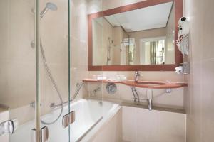 a bathroom with a sink and a shower and a tub at Hôtel Paris Louvre Opéra in Paris