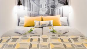 a bed with yellow and white pillows and flowers on it at Luxury Studio 24 in Győr