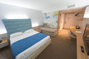 a bedroom with a bed and a table and a desk at Hotel Plaza - site du Futuroscope in Chasseneuil-du-Poitou