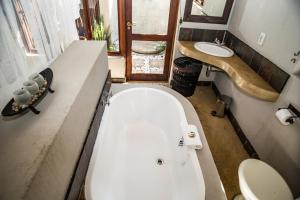 a bathroom with a tub and a toilet and a sink at Hoedspruit Raptors Lodge N16 in Hoedspruit