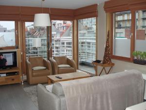 een woonkamer met een bank, stoelen en een tv bij Zonnig appartement in Nieuwpoort