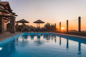 a swimming pool with chairs and a sunset in the background at Butterfly Villa in Theologos