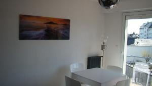 une salle à manger blanche avec une table et un tableau mural dans l'établissement residence arromanche, à Vannes