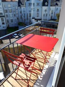 d'une table rouge et de deux chaises sur un balcon. dans l'établissement residence arromanche, à Vannes