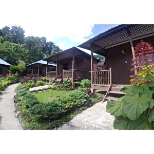 a building with a porch and a garden with flowers at ABC Chalet Tioman in Tioman Island