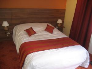 a bed in a hotel room with two pillows on it at Logis Hotel Restaurant Le Cheval Blanc in Charny