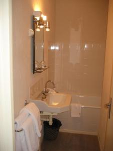 La salle de bains est pourvue d'un lavabo et d'une baignoire. dans l'établissement Logis Hotel Restaurant Le Cheval Blanc, à Charny