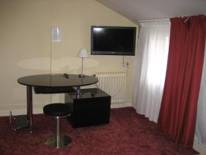 Habitación de hotel con mesa y TV en la pared en Logis Hotel Restaurant Le Cheval Blanc, en Charny