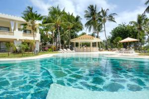 a swimming pool in front of a building with palm trees at Sandies Malindi Dream Garden in Malindi