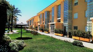 un grand immeuble avec un parasol dans la pelouse dans l'établissement Golden Beach II, à Jávea