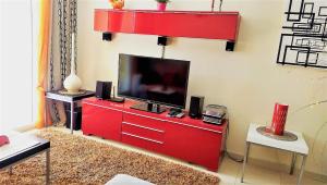 - un salon avec un centre de divertissement rouge et une télévision à écran plat dans l'établissement Golden Beach II, à Jávea