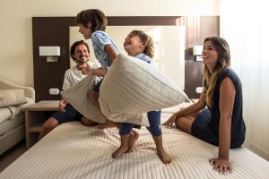 a group of people on a bed playing with pillows at Hotel Milano Helvetia - in centro con piscina in Riccione