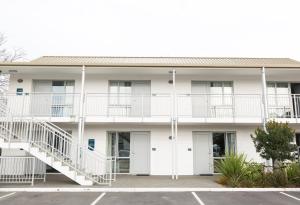 a white apartment building with white balconies and stairs at Airport Gateway Motor Lodge in Christchurch