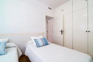 two beds in a bedroom with white cabinets and blue pillows at Vivaldi Valencia in Valencia