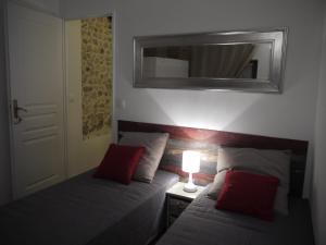 Vieille Ville 2 - La Petite Maison à Safranier, 2 bedrooms, max 4 adults and 2 kids في أنتيب: غرفة نوم بسريرين ومخدات حمراء ومرآة