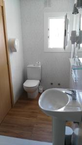 a white bathroom with a toilet and a sink at Costa HP in Castelldefels