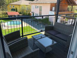 a balcony with two chairs and a table and a pool at Enjoyit Rooms in Velden am Wörthersee