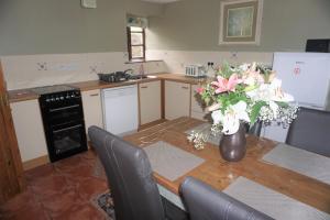 eine Küche mit einem Tisch und einer Blumenvase darauf in der Unterkunft Waterside Cottages in Waterhouses