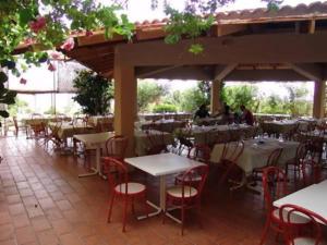 una fila di tavoli e sedie in un ristorante di Le Residenze di Porto Corallo a Villaputzu