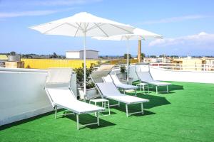 a row of white chairs and an umbrella on a roof at La Fenice Salentina in Alezio