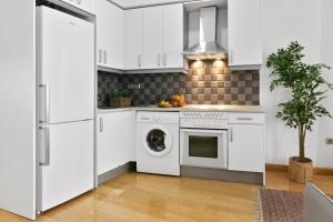 een keuken met witte kasten en een wasmachine en droger bij Gran Vía - Tu Apartamento Ideal para Disfrutar Madrid al Máximo in Madrid