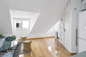 een woonkamer met witte muren en een tafel en stoelen bij Gran Vía - Tu Apartamento Ideal para Disfrutar Madrid al Máximo in Madrid