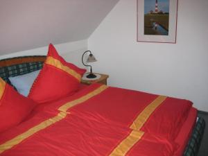 Cama con mantas y almohadas rojas y amarillas en Haus Pistorius, en Büsum