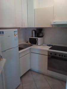 een kleine keuken met witte kasten en een magnetron bij Apartments Fuchs in Umag +32 foto's