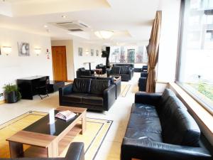 a living room with black leather couches and a table at London - Wembley International Hotel in London