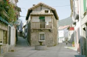 um pequeno edifício com uma varanda numa rua em Casa Rural de la Parra em La Adrada