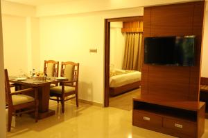 a room with a dining room table with a television at Hotel Karthika Park in Kazhakuttam