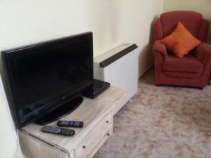 uma sala de estar com uma televisão e uma cadeira vermelha em Casa Rural de la Parra em La Adrada
