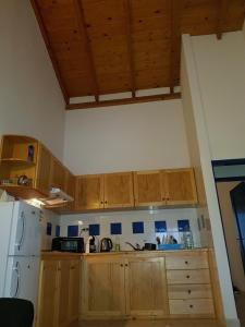 une cuisine avec des armoires en bois et un réfrigérateur blanc dans l'établissement Casa Azul SANTA MARIA Cape Verde, à Santa Maria