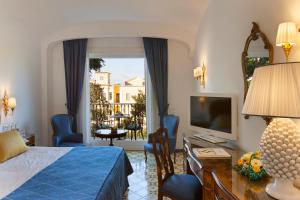 a bedroom with a bed and a desk and a television at Grand Hotel La Favorita in Sorrento