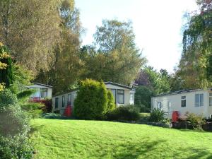 a row of houses in a grassy yard with trees at Linnhe Lochside Holidays in Corpach