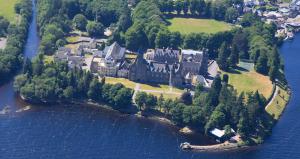 una casa grande en una isla en el agua en The Highland Club, en Fort Augustus