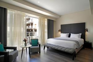 a bedroom with a bed and a chair and a window at Hotel Lozenge in Athens