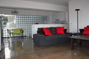 uma sala de estar com um sofá cinzento com almofadas vermelhas em Lichtdurchflutete Ferienwohnung mit Panorama-Sicht und Schwimmbad/Sauna em Muralto