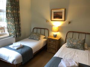 a bedroom with two beds and a lamp and a window at Tigh na Cheo in Kinlochleven