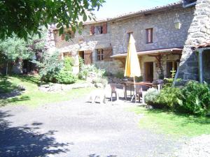 una casa con una mesa y una sombrilla amarilla en Notre Bergerie, en La Chaise-Dieu