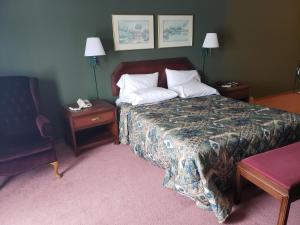 Habitación de hotel con cama y silla en Harbor Lights Lodge, en Kewaunee