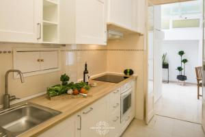 a kitchen with white cabinets and a sink at Historical Central Apartment with Interior Terrace 62 by Lisbonne Collection in Lisbon