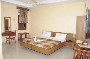 a bedroom with a bed and a desk and a chair at Hotel Chanma International in Coimbatore +32 photos