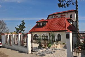 um edifício com um telhado vermelho e uma cerca em Casa Maria Arges em Piteşti