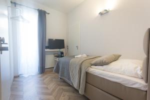 a white bedroom with a bed and a television at TM Suites in Dortmund