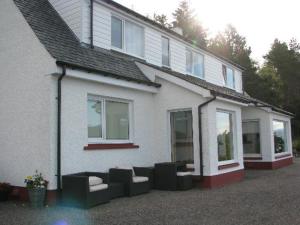 una casa blanca con muebles negros delante en Ardlair Guest House, en Ullapool