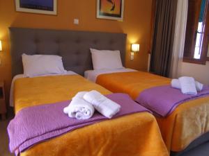 two beds in a hotel room with towels on them at Milos Studios in Parga