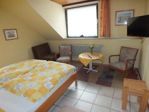 a bedroom with a bed and chairs and a tv at Gästehaus Neises in Minden